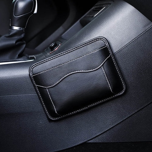 Black nylon car organizer box bag on an air vent, storing a phone and cards in a vehicle interior.
