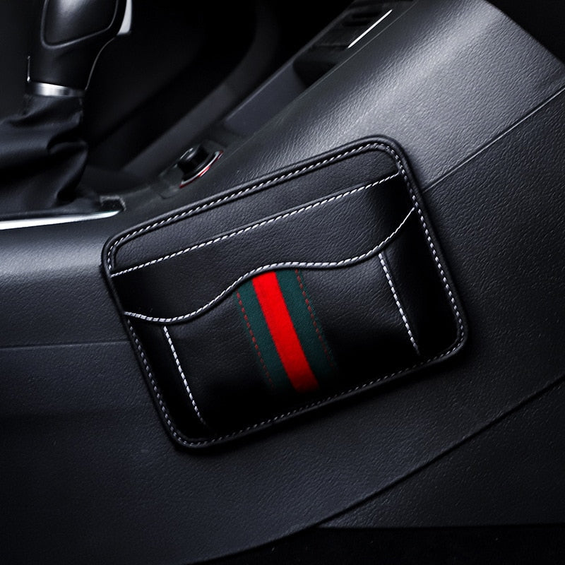 Black nylon car organizer box bag on an air vent, storing a phone and cards in a vehicle interior.